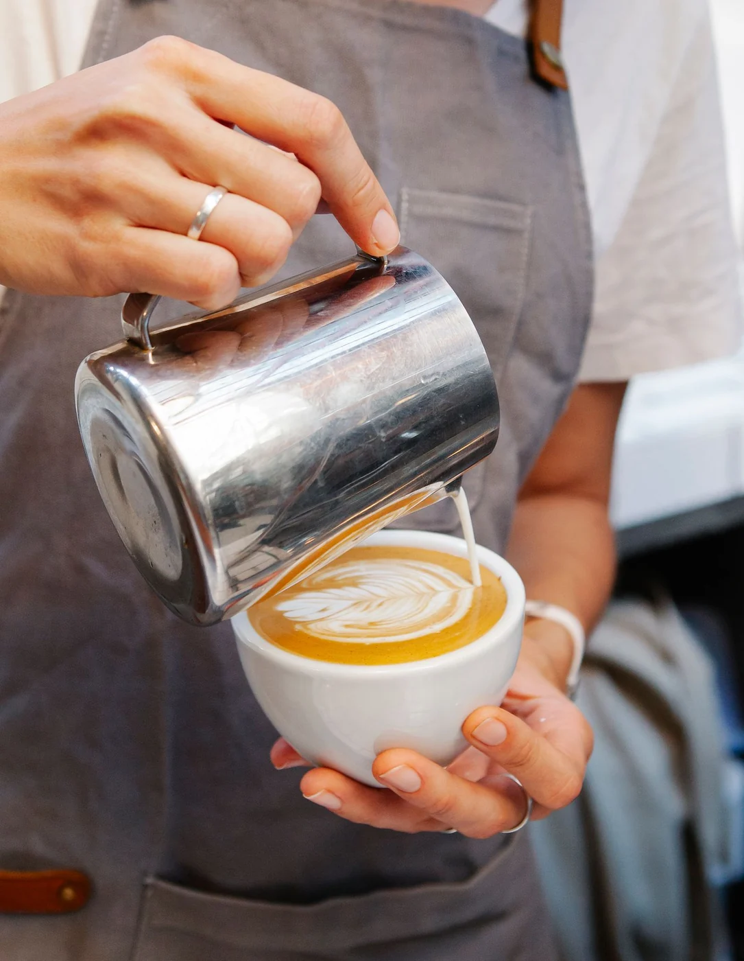 A barista pouring latte art into a cup at a hotel cafe